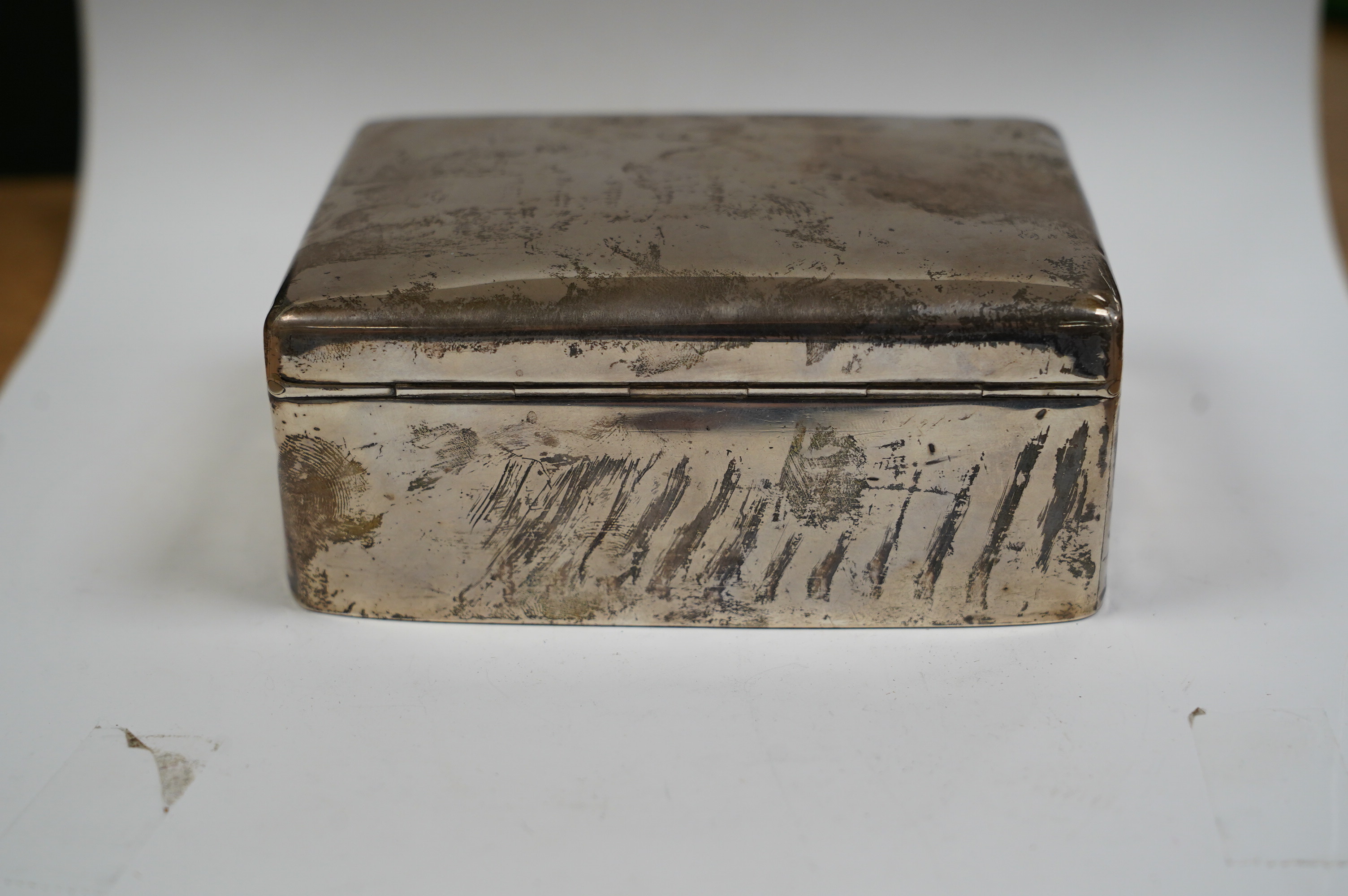 A George V silver mounted rectangular cigarette box, D. Bros, Birmingham, 1914, 12.4cm. Condition - poor